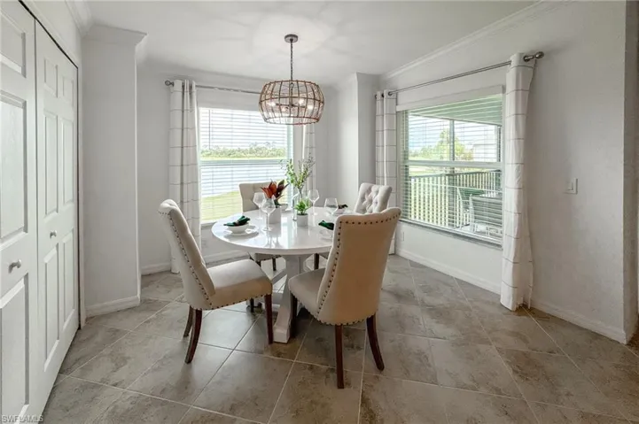 Dining room featuring plenty of natural light, ornamental molding, light tile patterned floors, and a chandelier
