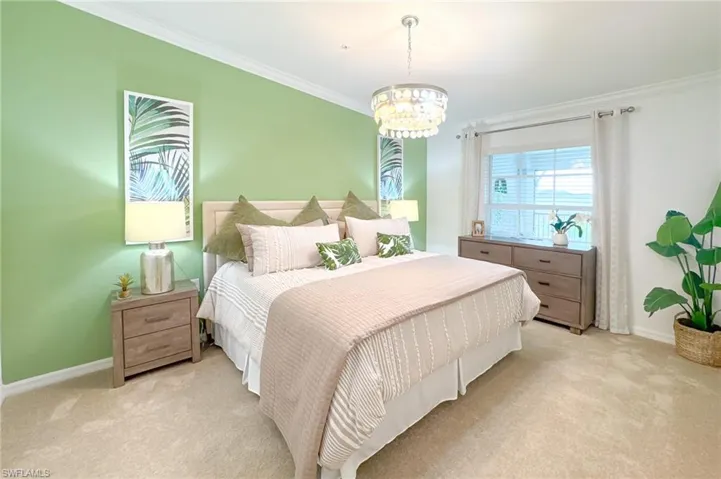 Carpeted bedroom featuring ornamental molding and a chandelier