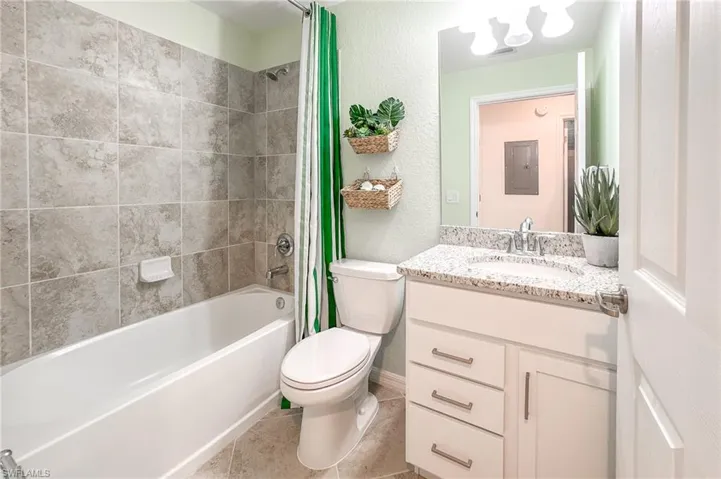 Full bathroom featuring tile patterned floors, vanity, shower / tub combo, a textured wall, and a chandelier