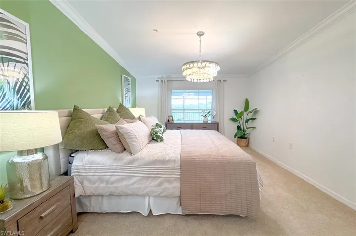 Carpeted bedroom featuring ornamental molding and a chandelier