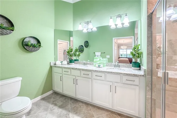 Bathroom with double vanity, a shower stall, ensuite bath, tile patterned flooring, and a textured wall