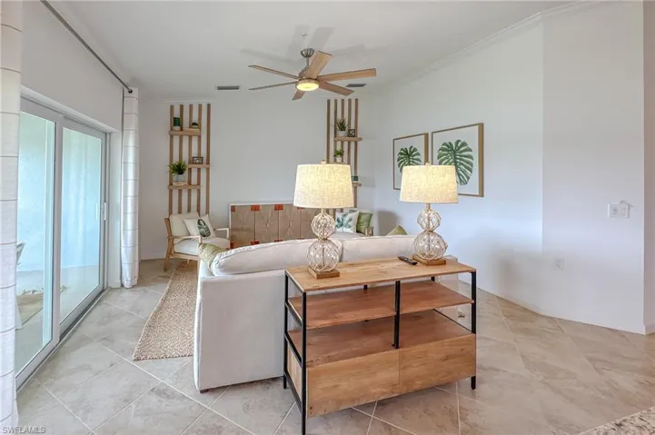 Living room featuring crown molding, ceiling fan, and light tile patterned flooring