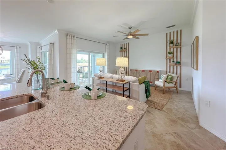 Kitchen featuring ornamental molding, light stone countertops, a ceiling fan, and light tile patterned floors