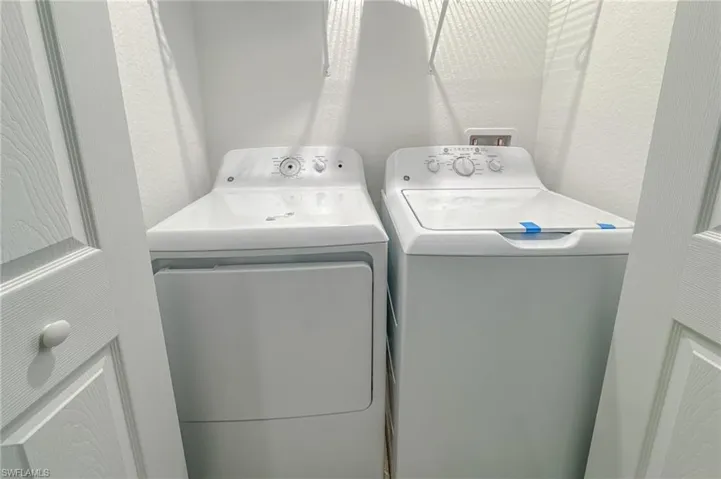 Laundry room with washing machine and clothes dryer and a textured wall