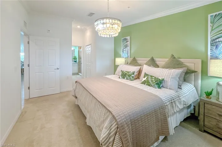Bedroom with ornamental molding, light carpet, a chandelier, and ensuite bathroom