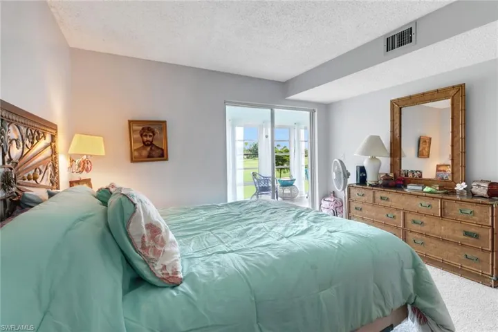 Bedroom featuring a textured ceiling, access to exterior, and carpet