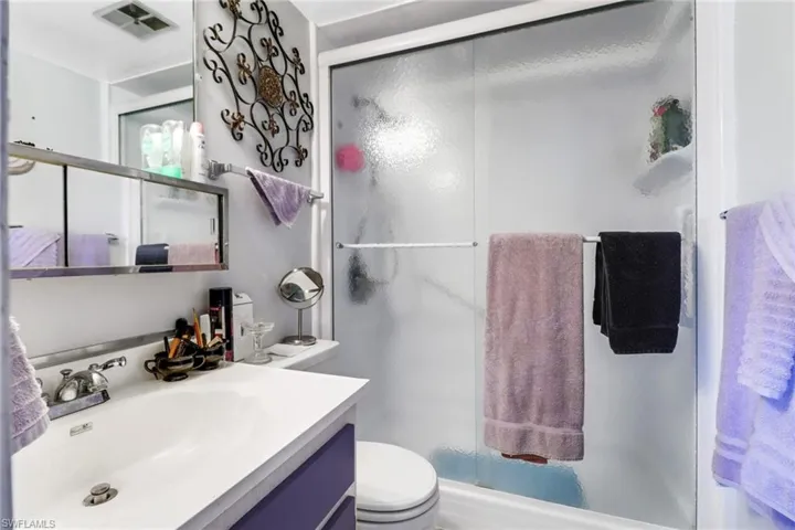 Bathroom featuring walk in shower, vanity, and toilet