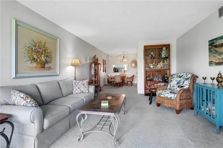 Living room with an inviting chandelier, a textured ceiling, and carpet