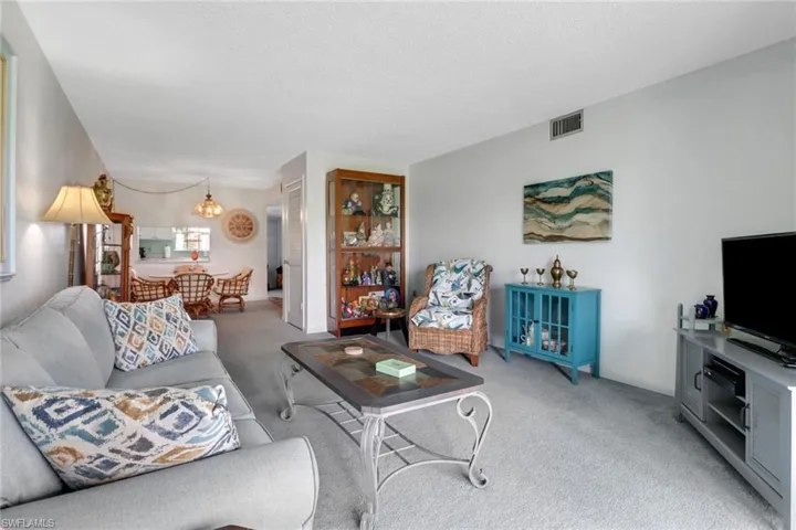 Living room featuring light carpet, a chandelier, and a textured ceiling