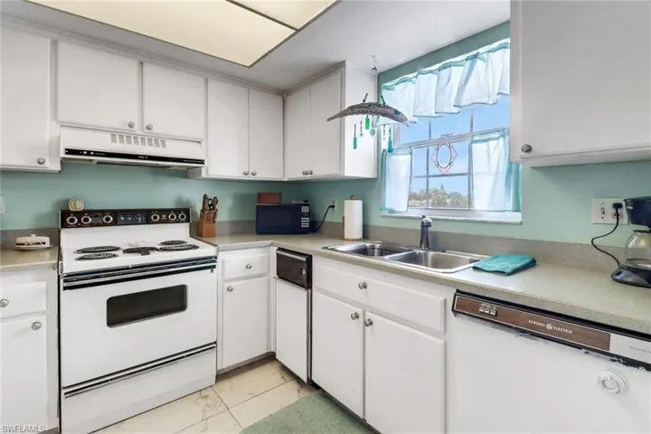 Kitchen with white cabinets, white appliances, and sink