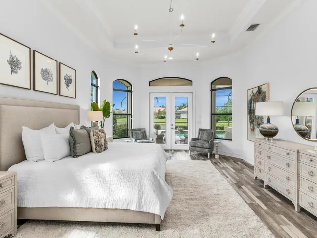 Bright and open bedroom with custom arched windows and tray ceiling.