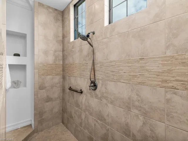 Walk-through tiled shower with storage built-ins.