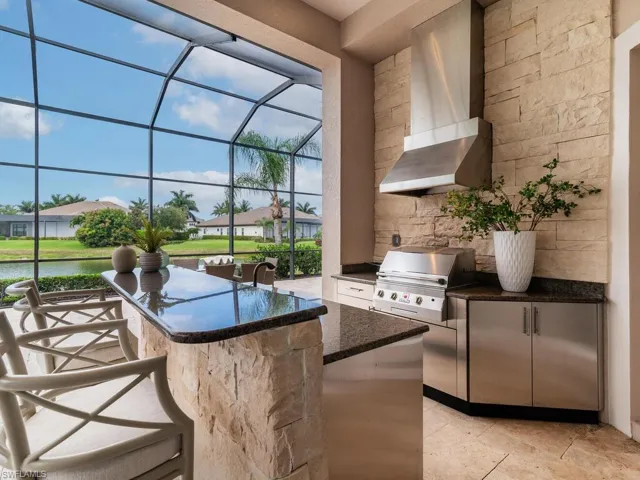 Outdoor kitchen with fridge, sink, grill, and storage.