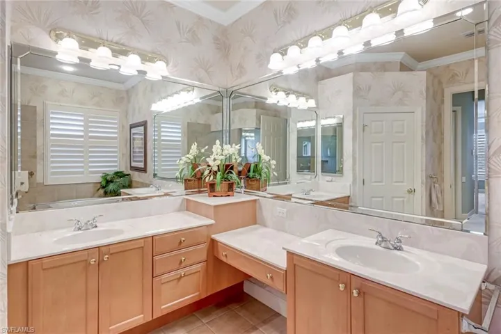 Full bath with ornamental molding, two vanities, light tile patterned floors, and wallpapered walls