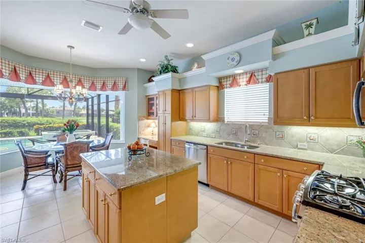 Kitchen featuring backsplash, light stone counters, a center island, a chandelier, and recessed lighting