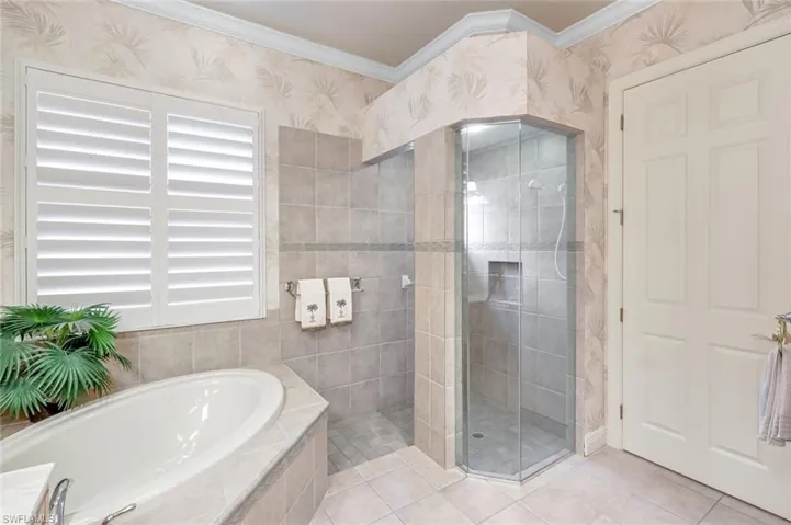 Bathroom with a shower stall, a bath, wallpapered walls, crown molding, and light tile patterned floors