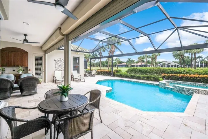 View of swimming pool featuring a patio area, a sunroom, a pool with connected hot tub, ceiling fan, and glass enclosure