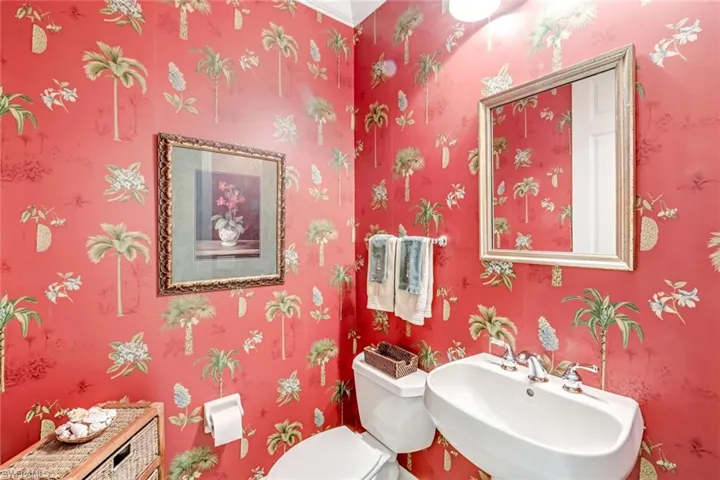 Convenient Half Bathroom with crown molding and stylish wallpaper