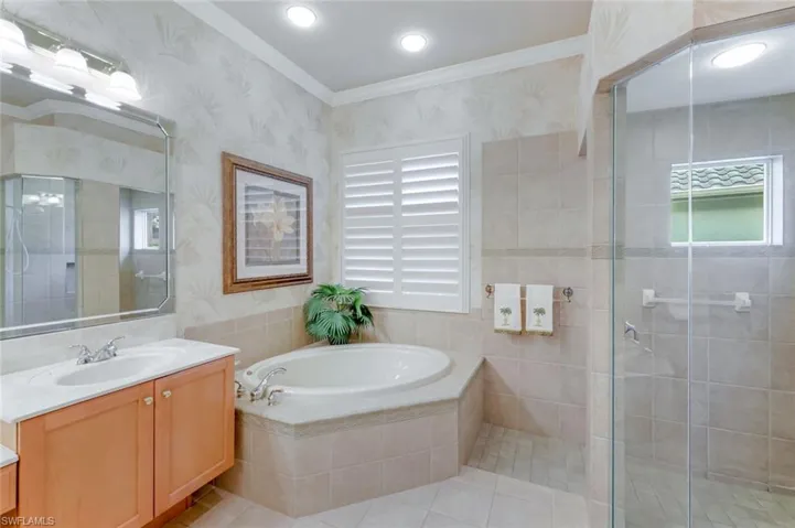 Full bath with vanity, ornamental molding, wallpapered walls, a shower stall, and a bath