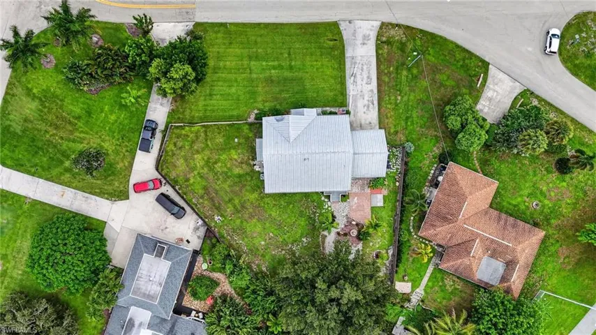 Expansive lot featuring a primary residence with a gray roof and concrete driveway