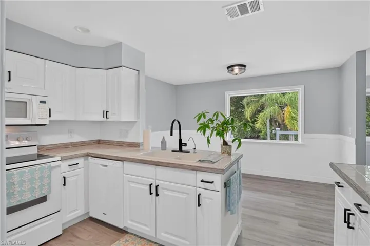 Modern kitchen featuring white cabinetry, light wood-finish countertops, and stainless steel appliances