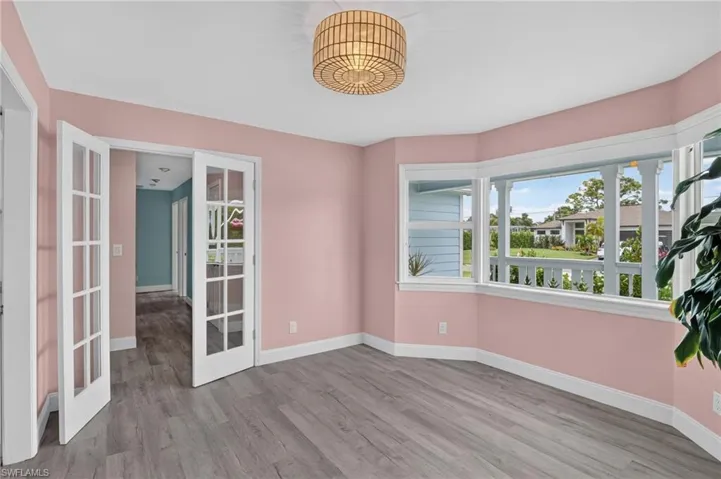 Bay window, wood-finish flooring, French doors, recessed lighting, and a drum pendant light fixture