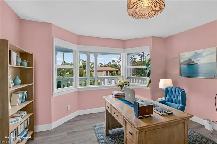 Recessed bay window, wood-finish flooring, built-in shelving, decorative ceiling fixture, and light-toned walls