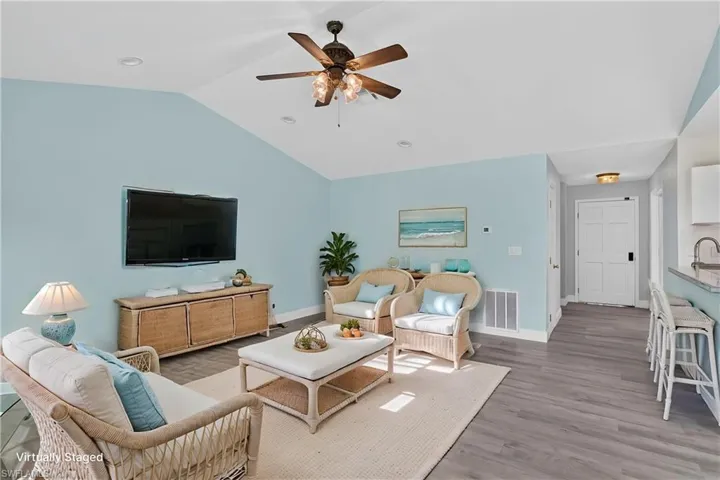 Vaulted ceiling, wood-finish flooring, ceiling fan with light fixture, recessed lighting, and a paneled interior door