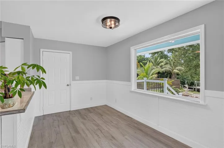 Wood-finish flooring, white wainscoting, and a ceiling-mounted light fixture