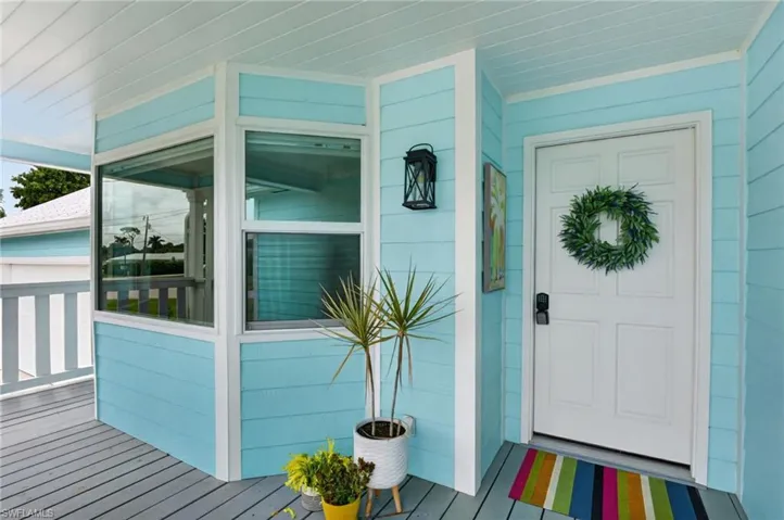 Exterior featuring a white paneled door, black lantern-style wall sconce, and a wrap-around porch with light blue siding