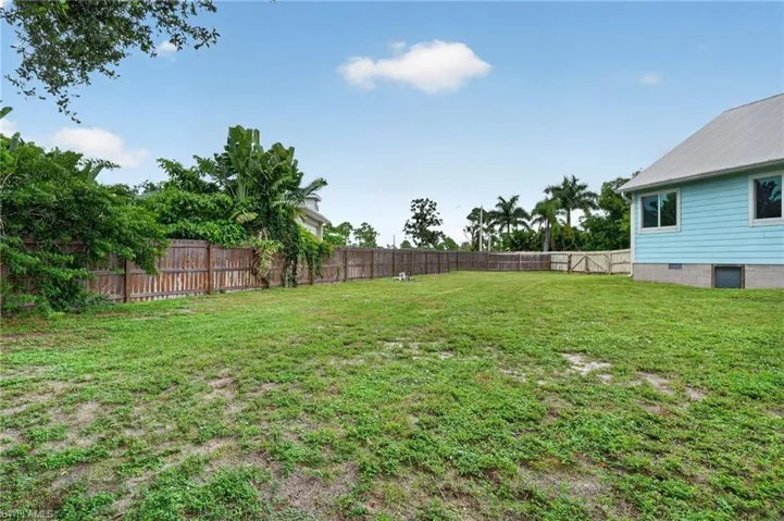 Expansive backyard featuring a wood fence, mature landscaping, and a side gate