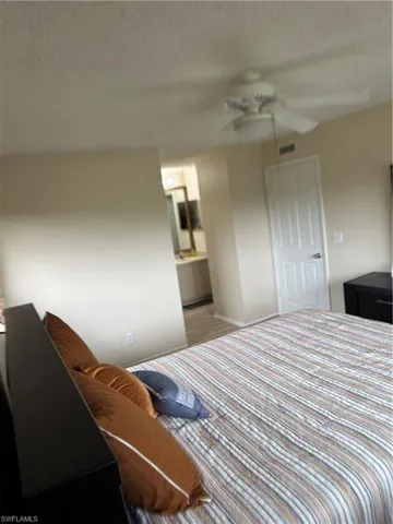 Bedroom with connected bathroom, a textured ceiling, and ceiling fan