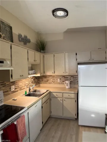 Kitchen featuring range, white fridge, light countertops, backsplash, and dishwasher