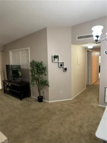 Living room with carpet floors, a textured ceiling, and a chandelier