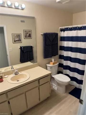 Bathroom featuring light wood-style flooring, vanity, and curtained shower