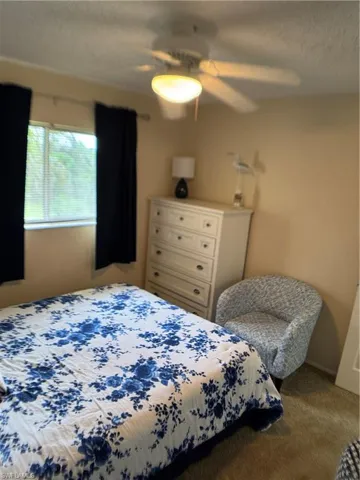 Carpeted bedroom featuring a textured ceiling and ceiling fan