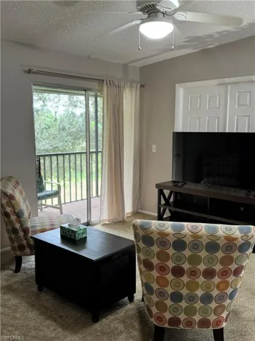 Carpeted living area featuring a ceiling fan and a textured ceiling