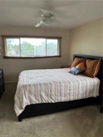 Carpeted bedroom featuring a ceiling fan and baseboards