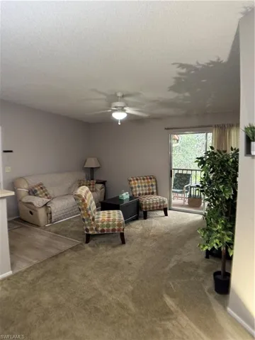 Carpeted living area with a ceiling fan and a textured ceiling