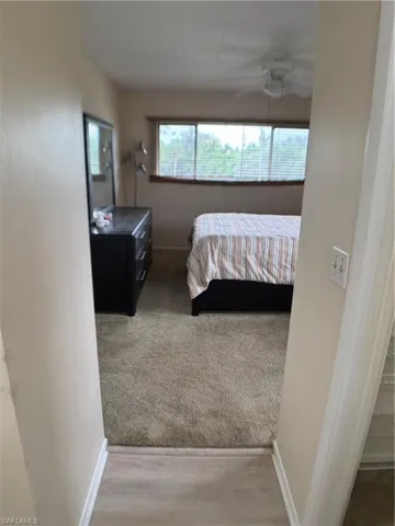 Carpeted bedroom featuring wood finished floors and a ceiling fan