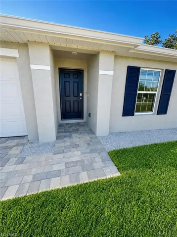 (Digitally Enhanced) Stucco exterior featuring a recessed entry, multi-panel front door, decorative window shutters, and a paved walkway