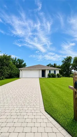 (Digitally Enhanced) Single-story exterior featuring a stone-paver driveway, a two-car garage, and a hip roofline