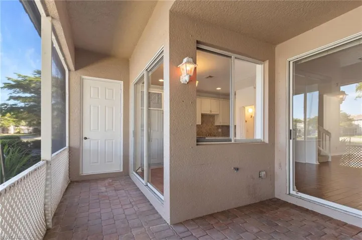 Unfurnished sunroom with a textured wall and brick floors