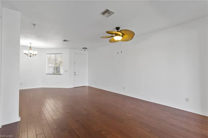 Unfurnished room featuring dark wood-type flooring, ceiling fan, and a chandelier