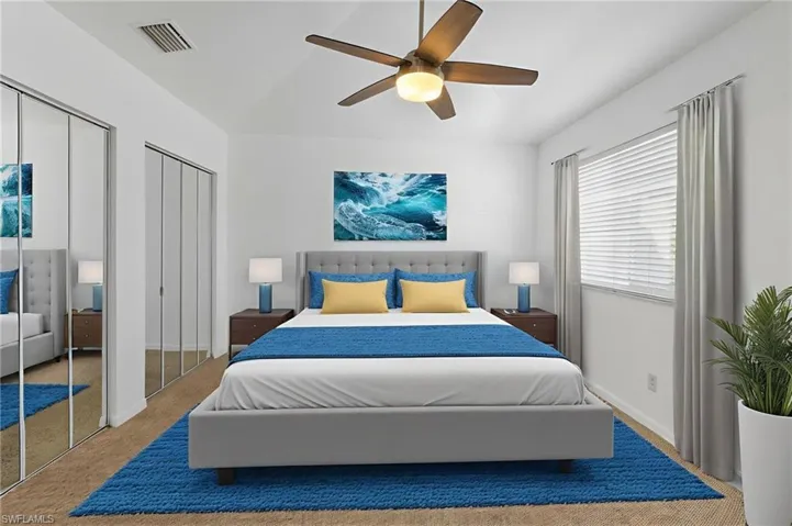 Carpeted bedroom with multiple closets, lofted ceiling, and a ceiling fan