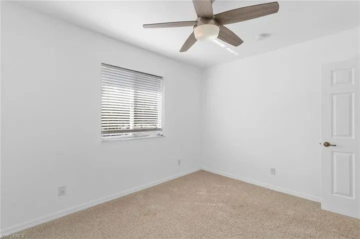 Carpeted empty room with baseboards and ceiling fan