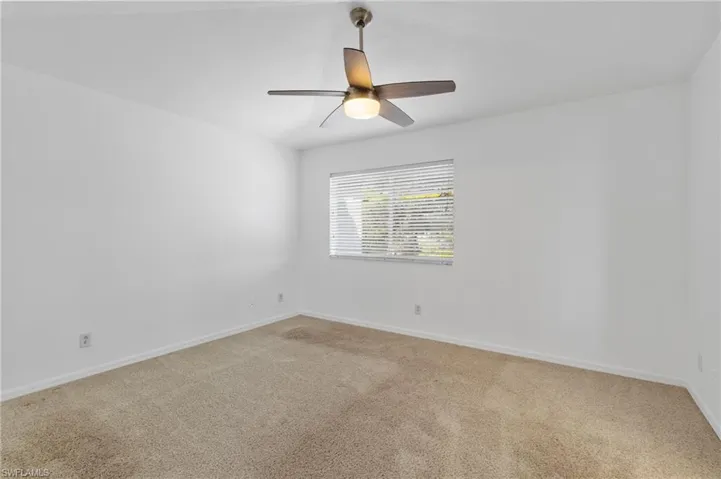 Spare room featuring light carpet and ceiling fan