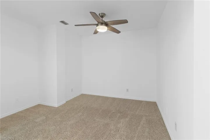 Carpeted spare room with baseboards and ceiling fan