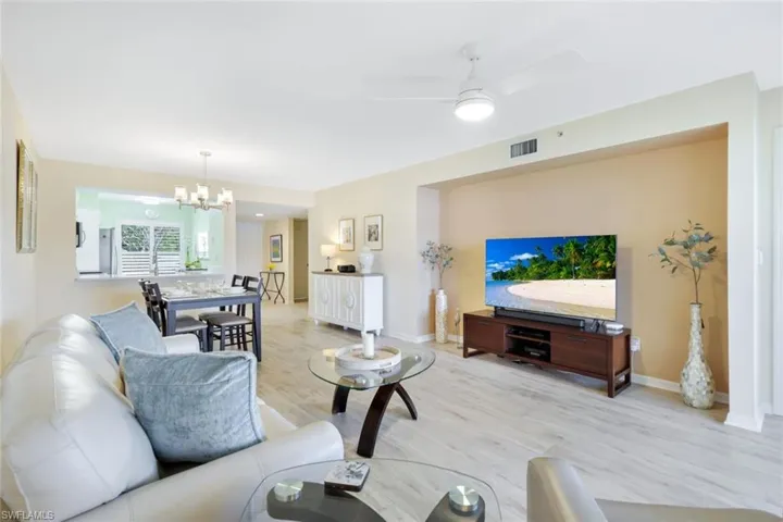 Living room with hardwood / wood-style flooring and ceiling fan with notable chandelier
