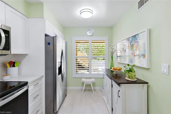 Kitchen with stainless steel appliances, white cabinetry, a textured ceiling, and light tile floors